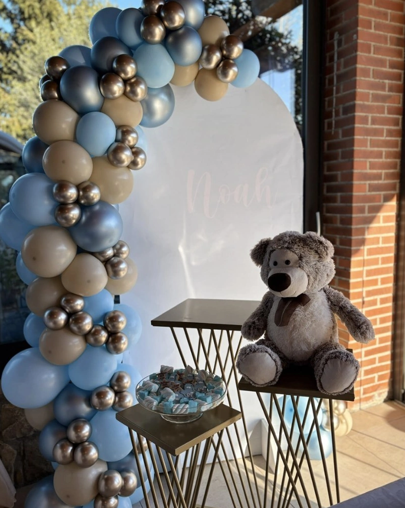 Pannello con palloncini azzurri e oro, orso e tavolini